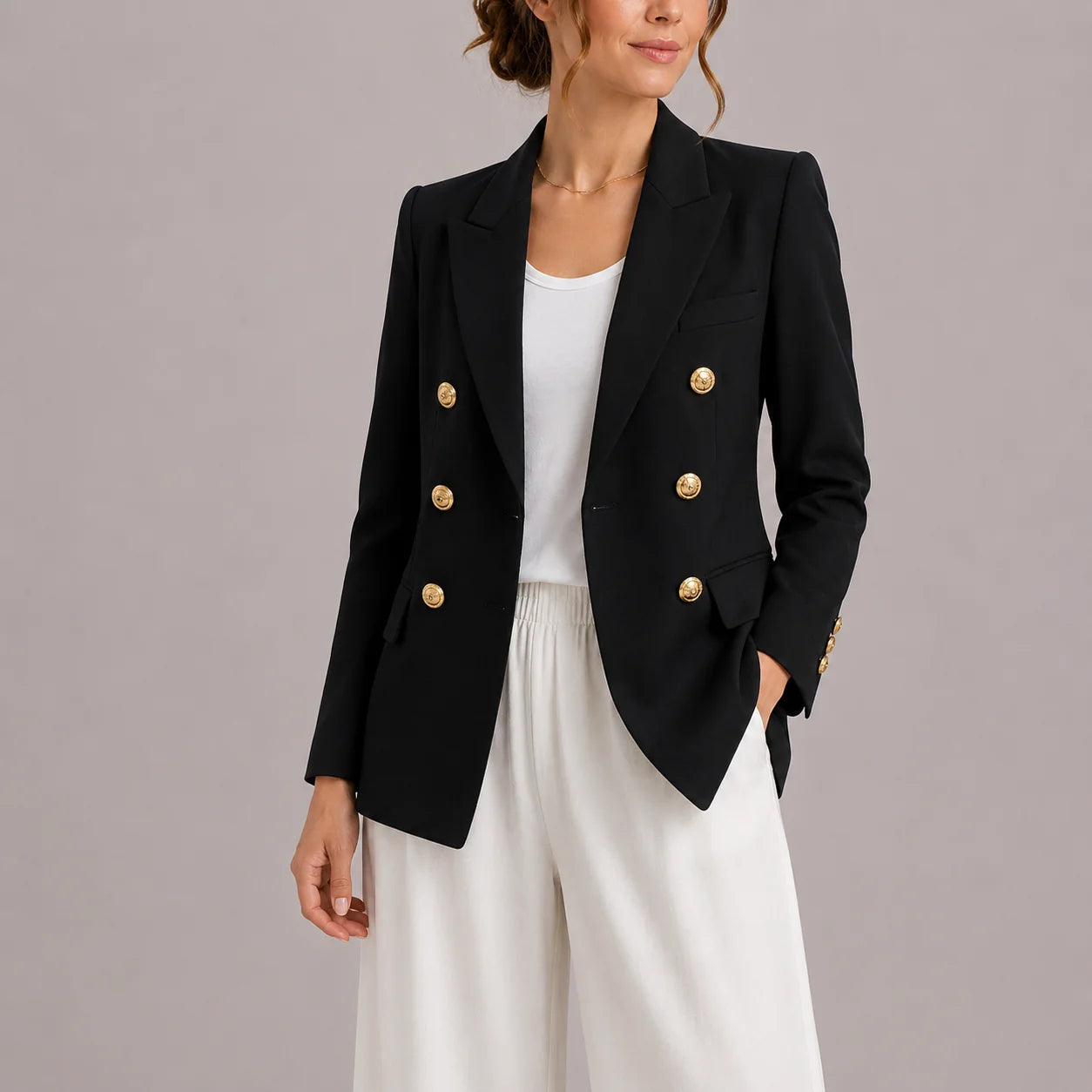 Women's black double-breasted blazer with gold-tone buttons and notched lapels worn over white top