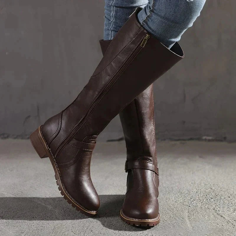Women's knee-high boots in brown with side zip and buckle detail worn with jeans