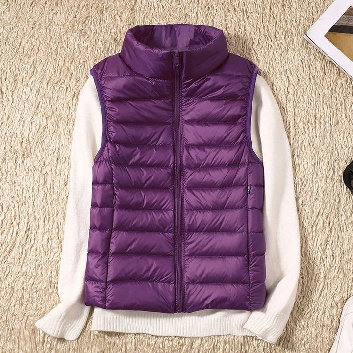 Women's hip-length quilted gilet styled with white jumper and casual trousers for layered look