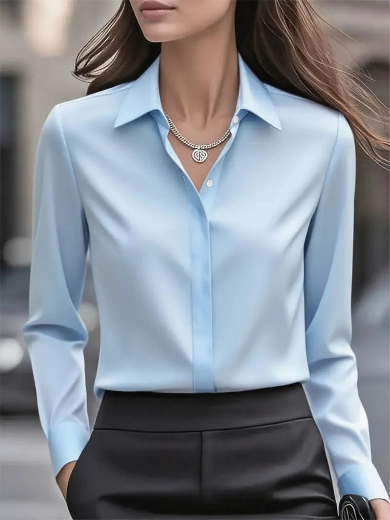 Close-up of smooth satin fabric texture and button detail on women's blouse