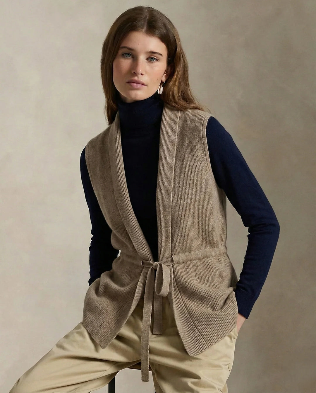 Woman wearing the beige vest with the waist tie fastened for a tailored look