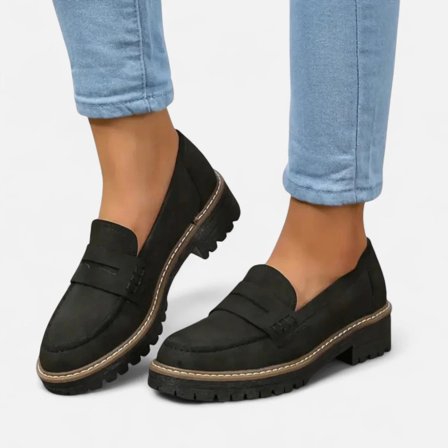 Women's chunky loafers in black with cleated sole and slip-on design worn with light blue jeans