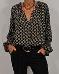 Women's geometric print blouse with deep V-neckline and ruffle collar detail, styled with black trousers