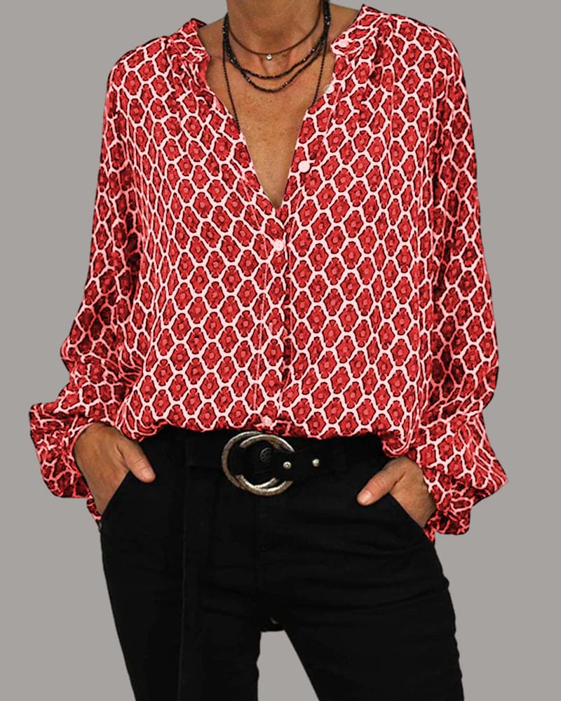 Women's geometric print blouse with long sleeves and ruffle cuffs, worn untucked over black trousers