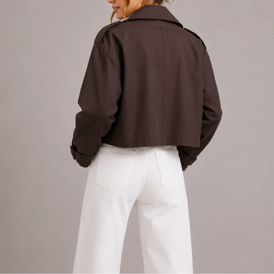Close-up view of cropped trench jacket showing structured fabric and shoulder epaulette detail