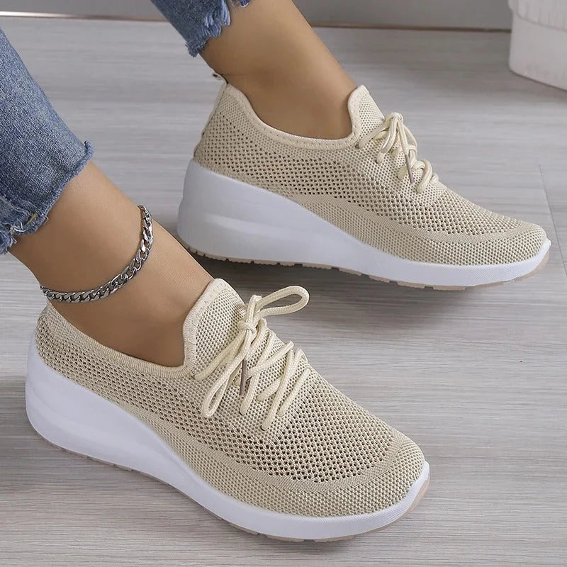 Women's knit trainers in beige with lace-up closure and chunky white sole on feet