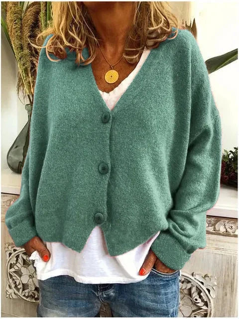 Woman wearing teal relaxed knit cardigan with V-neckline and button front over white tee