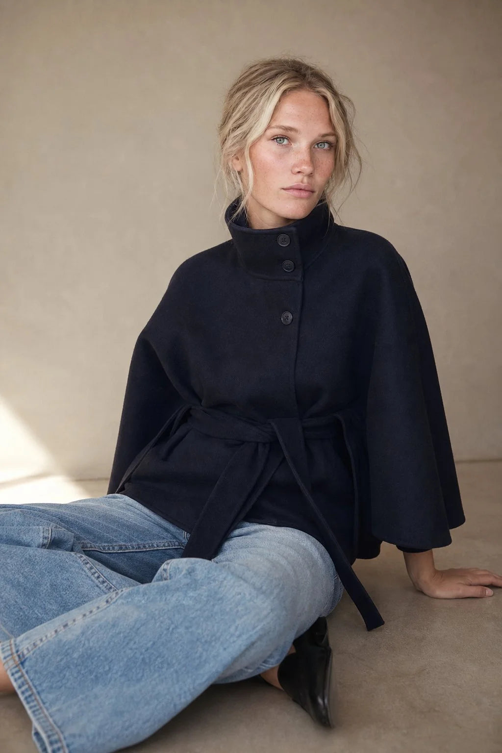 Close-up of wool cape coat showing structured stand collar and button fastening