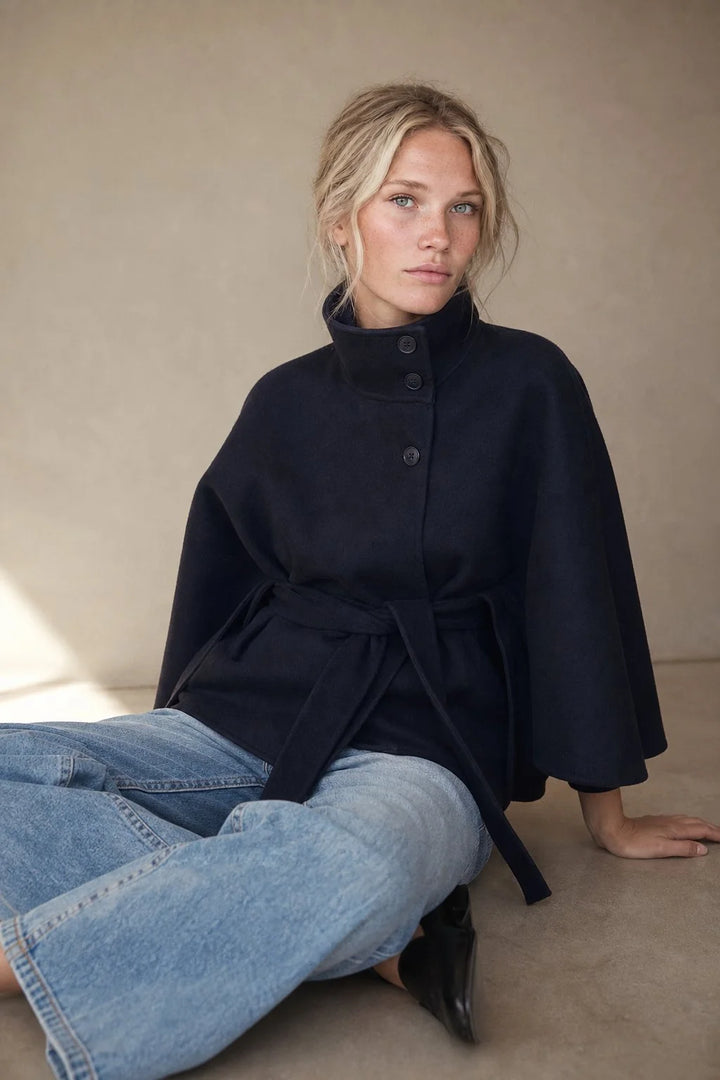 Close-up of wool cape coat showing structured stand collar and button fastening