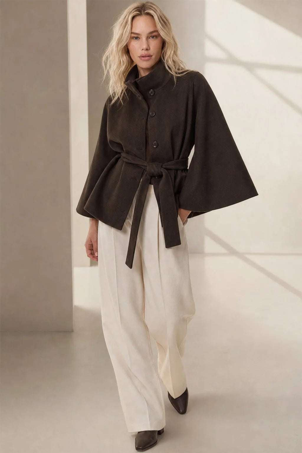 Side view of women's cape coat displaying flowing cape sleeves and tailored silhouette