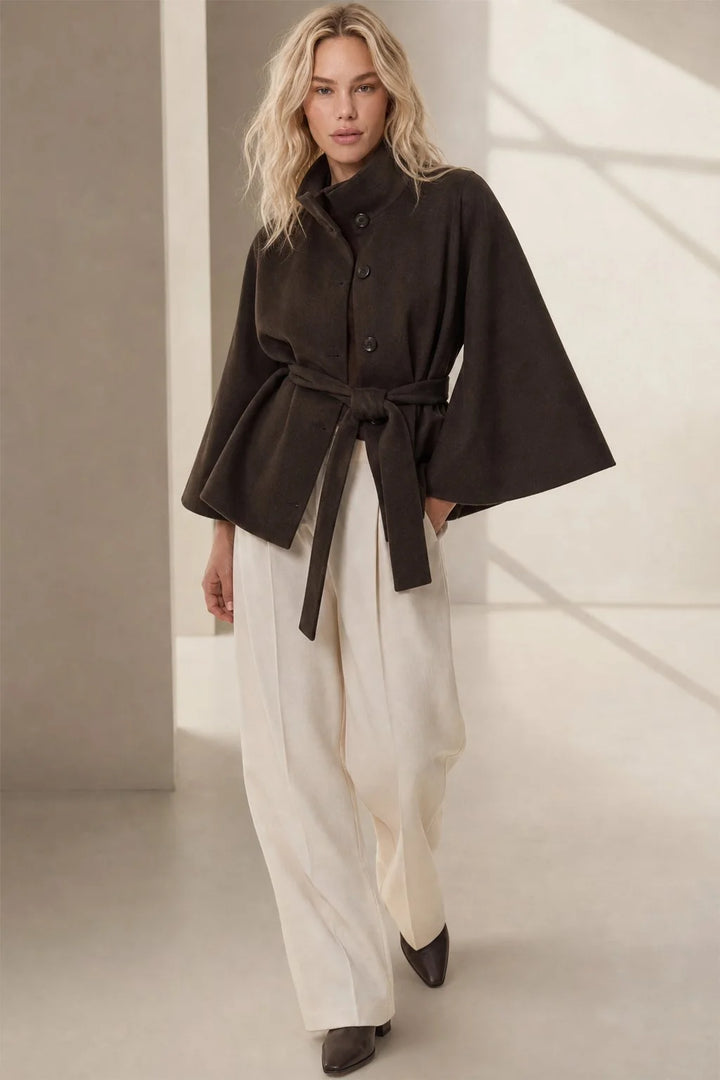 Side view of women's cape coat displaying flowing cape sleeves and tailored silhouette