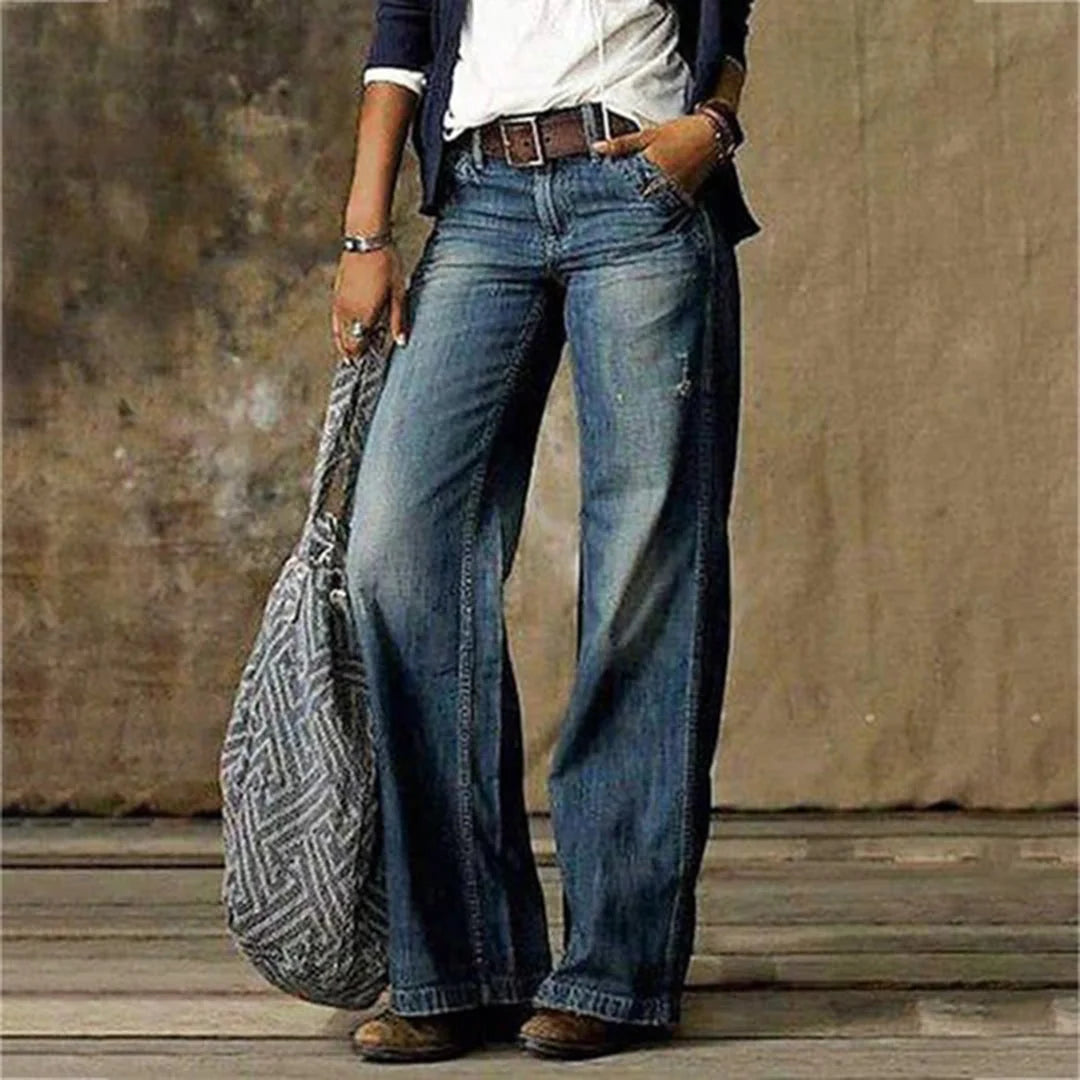 Close-up of vintage wash wide leg jeans showing distressed detailing and whiskering at the thigh