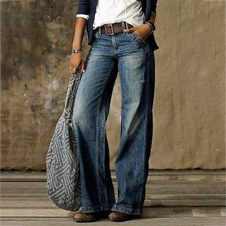 Close-up of vintage wash wide leg jeans showing distressed detailing and whiskering at the thigh