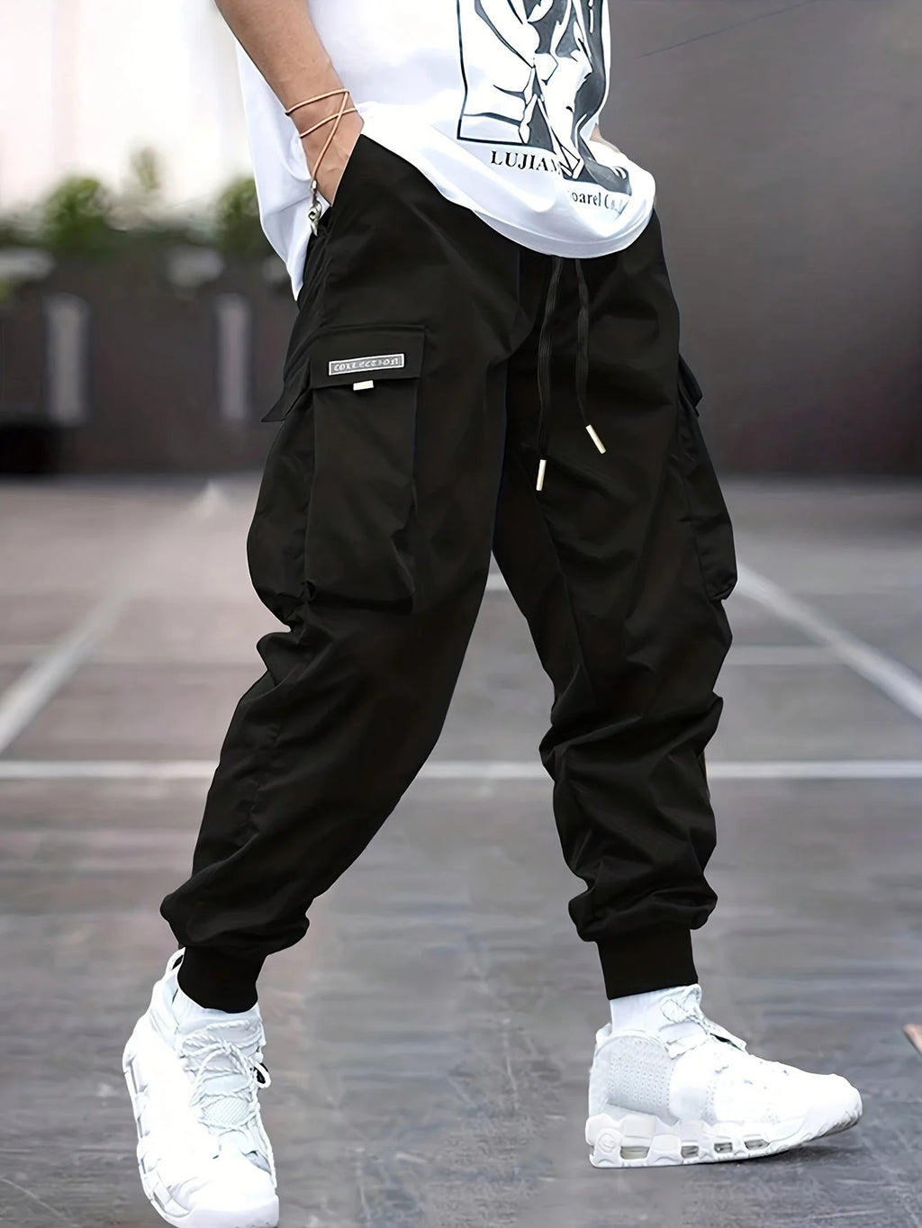 Men's cargo trousers in black with elasticated ankle cuffs and multiple pockets worn with white trainers