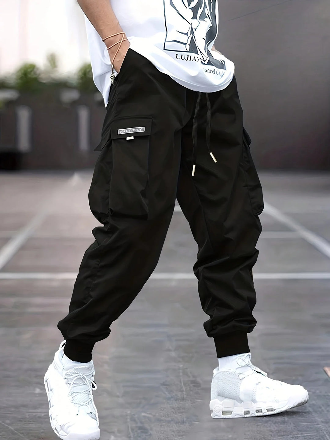 Men's cargo trousers in black with elasticated ankle cuffs and multiple pockets worn with white trainers