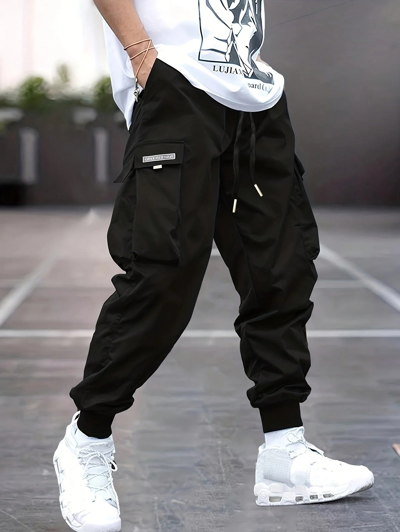 Men's cargo trousers in black with elasticated ankle cuffs and multiple pockets worn with white trainers