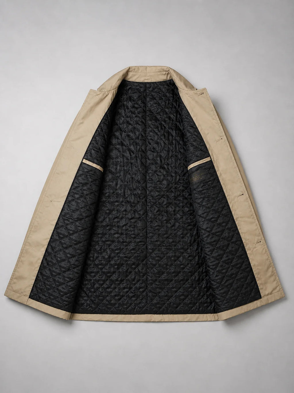 Detail shot of beige coat's functional pocket and button closure with clean tailored lines and woven fabric texture