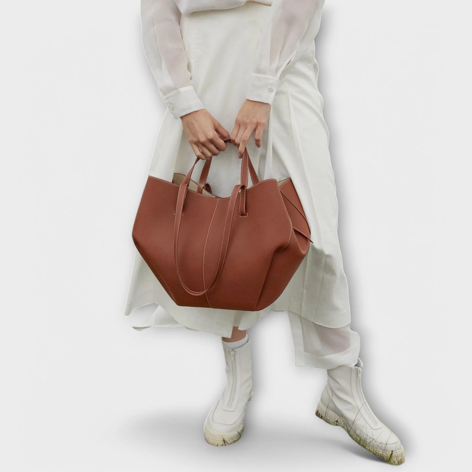 Taupe curved tote bag styled for everyday use with dual carrying handle options