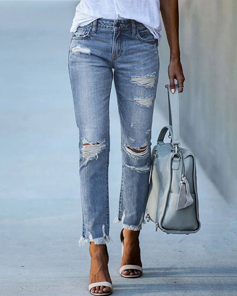 Women's distressed straight leg jeans with ripped knees and frayed hem worn with white tee