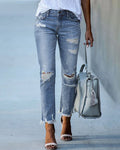 Women's distressed straight leg jeans with ripped knees and frayed hem worn with white tee