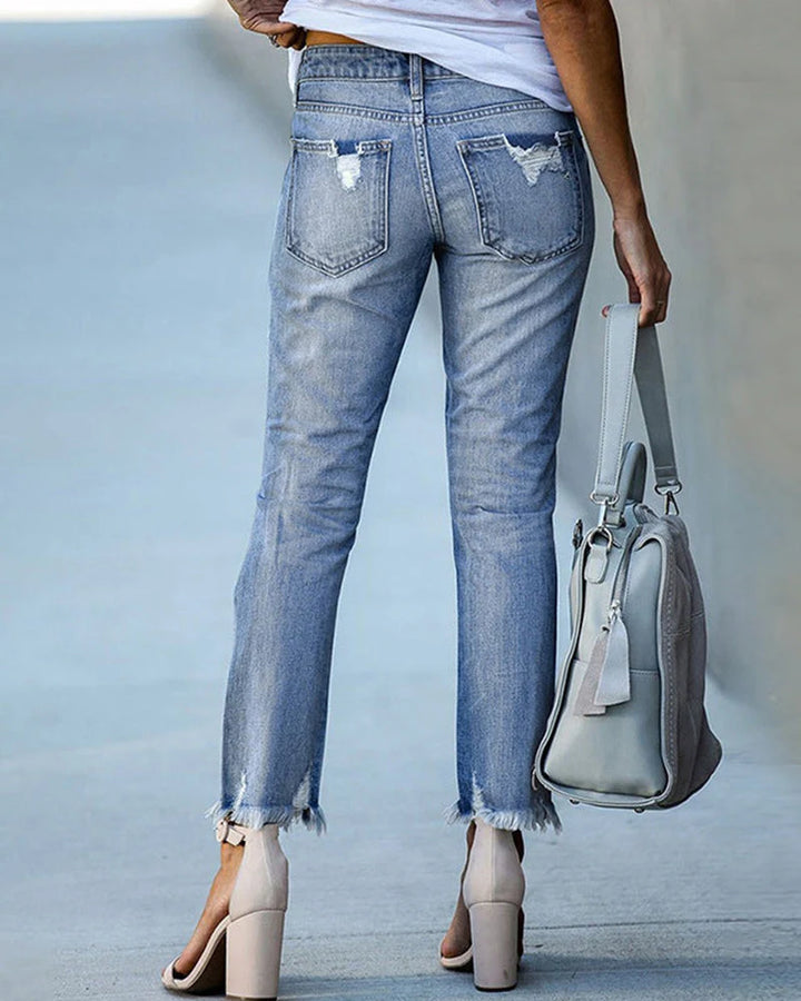 Mid-rise distressed jeans showing straight leg silhouette and cropped length detail