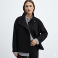 Women's relaxed wool coat in black with high neckline and double-breasted button closure worn over striped shirt