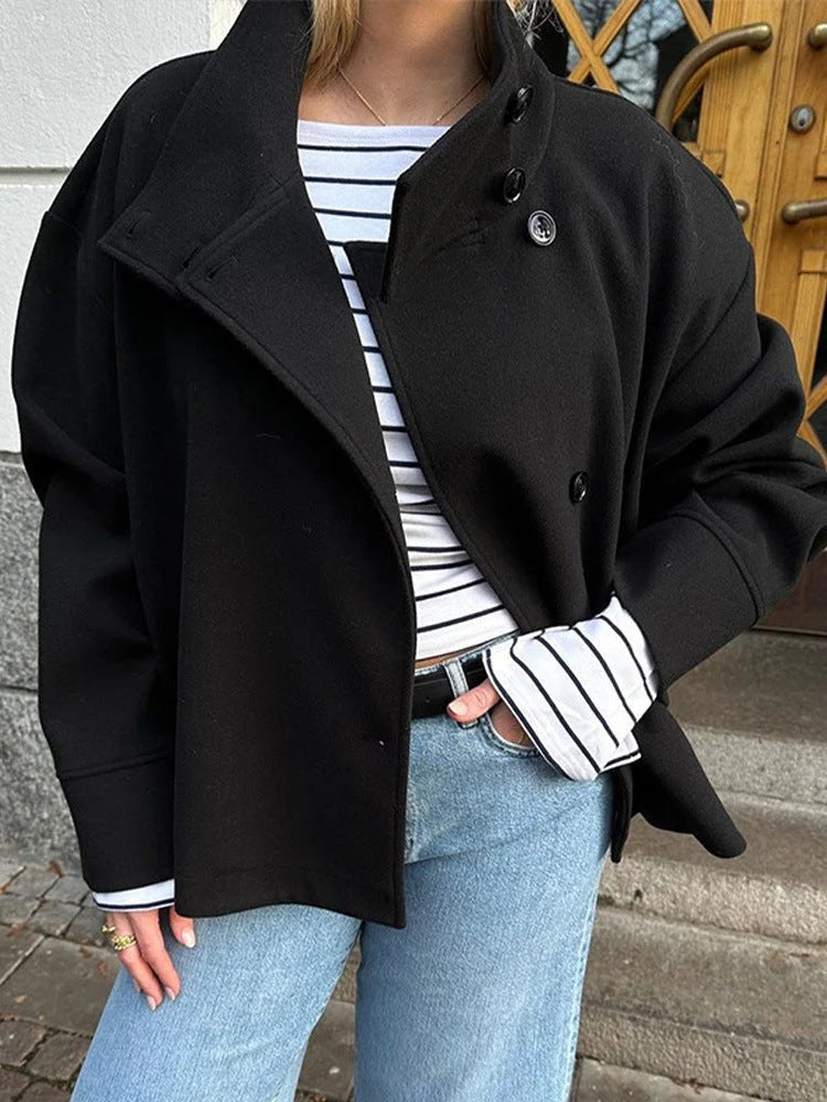 Women's black wool coat styled with striped shirt and tailored trousers for casual layering