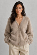 Woman wearing beige fluffy knit cardigan with button-front closure and relaxed fit over cream trousers