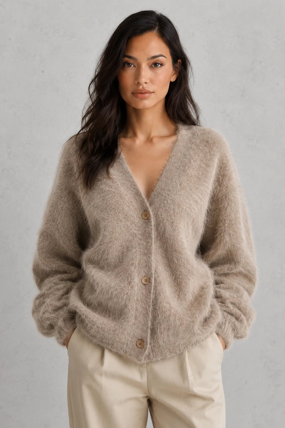 Woman wearing beige fluffy knit cardigan with button-front closure and relaxed fit over cream trousers