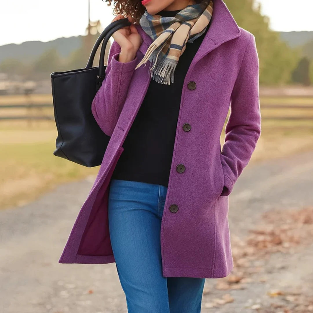 Woman styling camel wool coat over black top and blue jeans with scarf accessory
