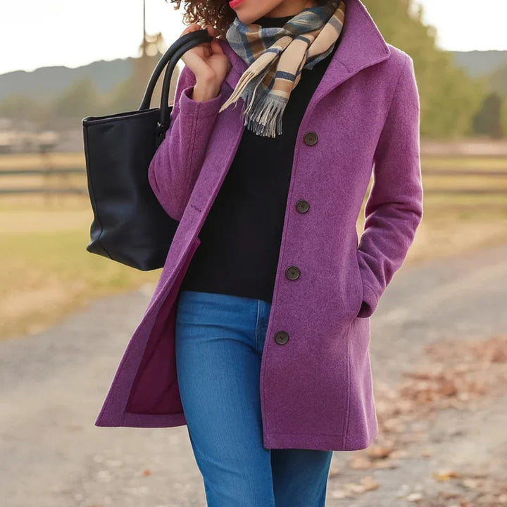 Woman styling camel wool coat over black top and blue jeans with scarf accessory
