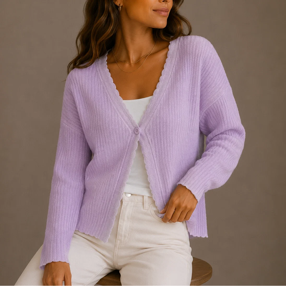 Detail shot of single button fastening and scalloped trim on women's knit cardigan