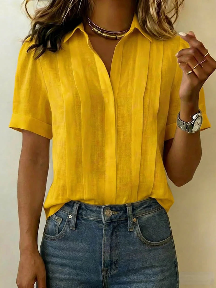 Detail of pleated front blouse collar and V-neckline showing woven fabric texture and construction