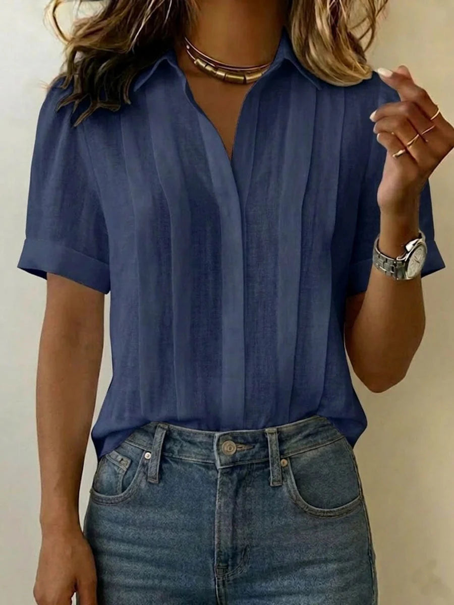 Full view of pleated front blouse showing short sleeves curved hem and relaxed fit silhouette