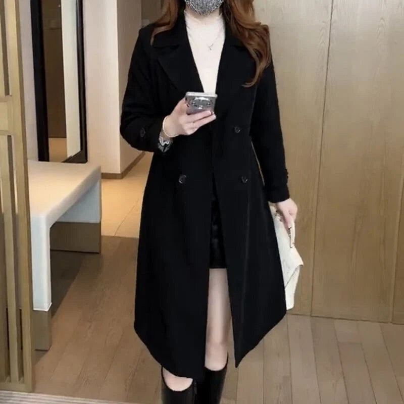 Women's black double-breasted trench coat with notched lapels and mid-length cut worn over white top