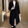 Women's black double-breasted trench coat with notched lapels and mid-length cut worn over white top