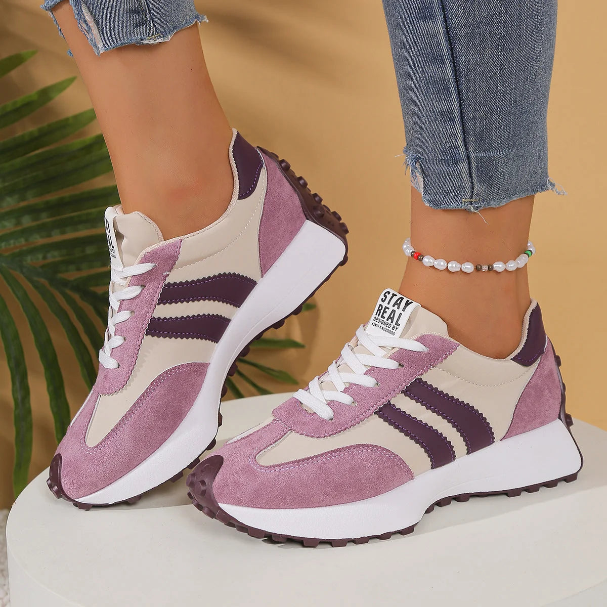Full view of women's retro athletic trainers in burgundy with white stripes and gum outsole