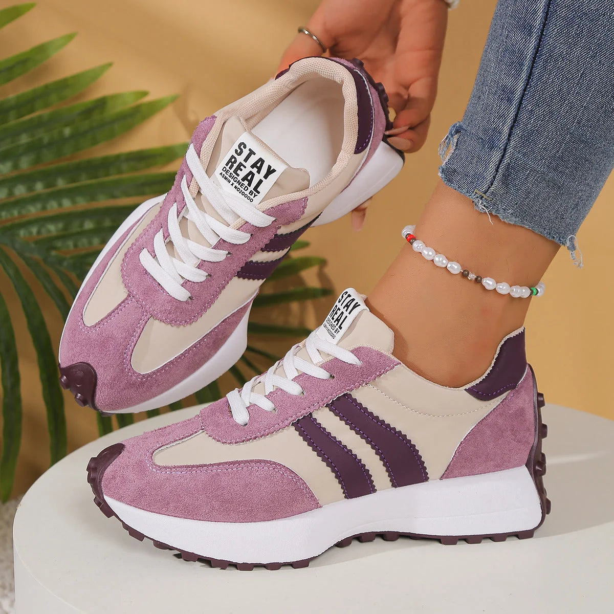 Detail of women's retro trainers showing textured suede upper and white contrast stripes
