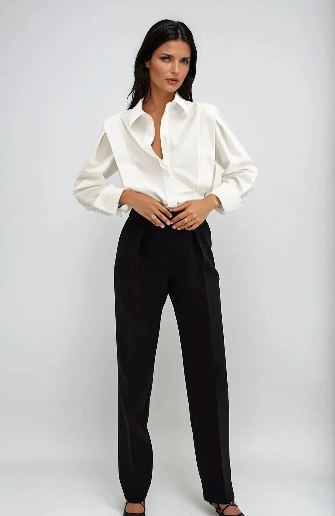 Women's white collared shirt with structured shoulders and long cuffed sleeves styled with black trousers