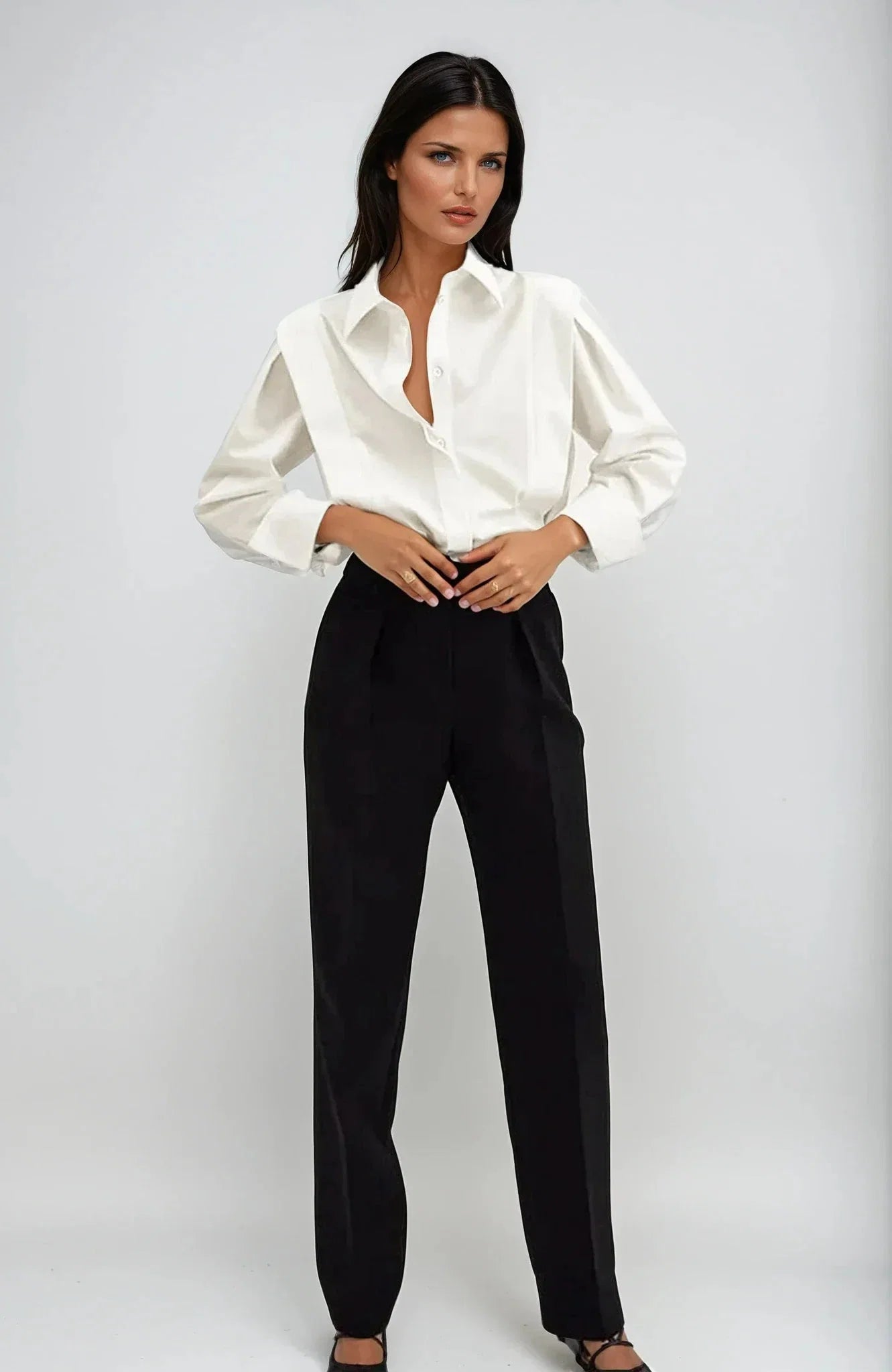 Women's white collared shirt with structured shoulders and long cuffed sleeves styled with black trousers