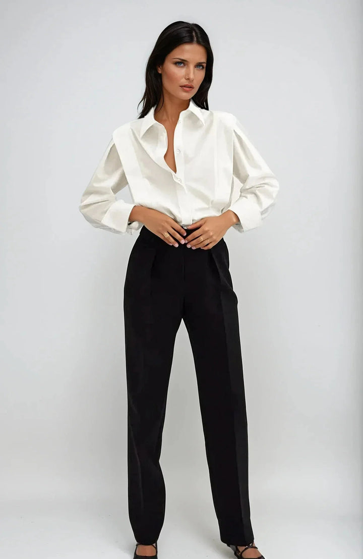 Women's white collared shirt with structured shoulders and long cuffed sleeves styled with black trousers