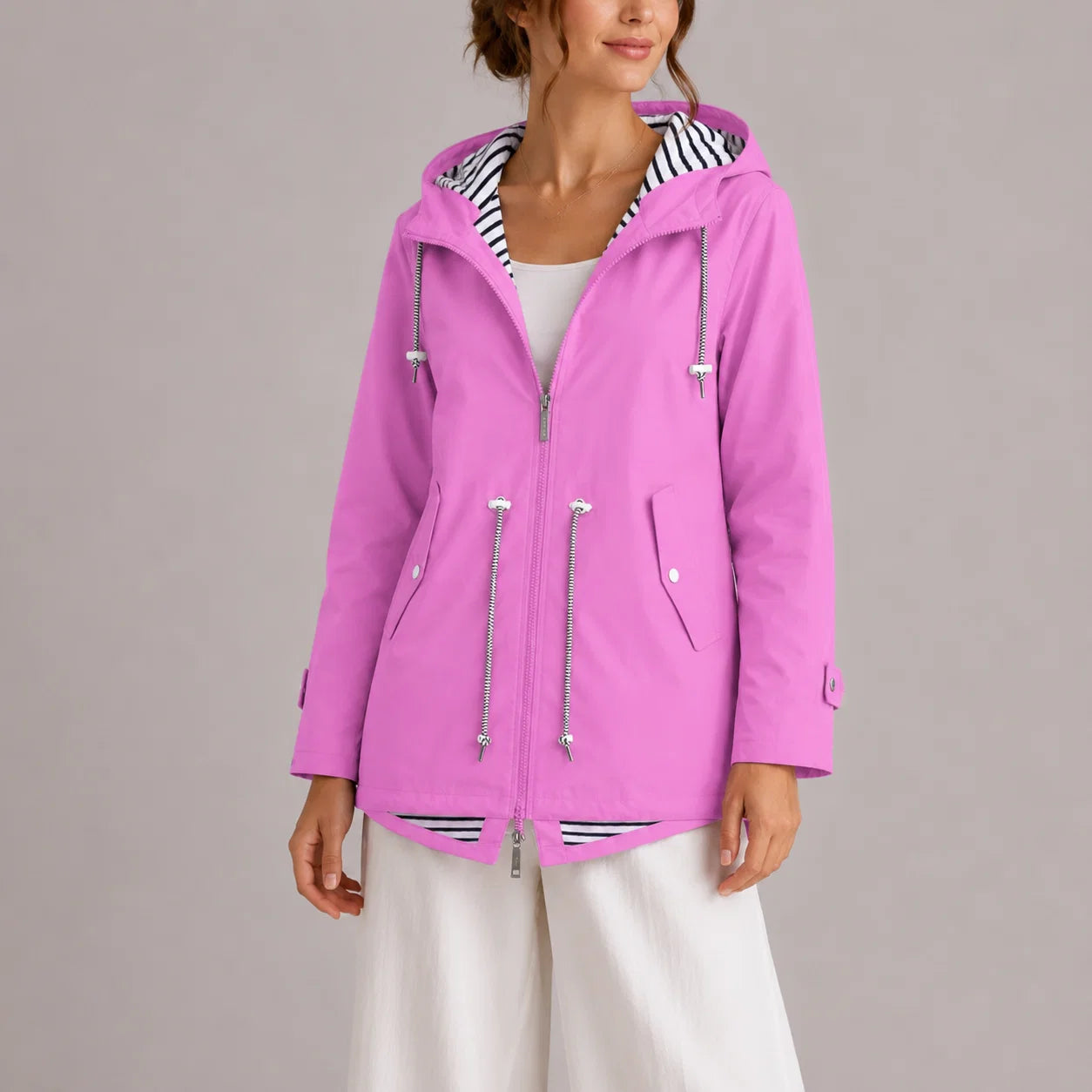 Women's hooded raincoat with zip-front closure and striped lining detail, shown in orchid pink