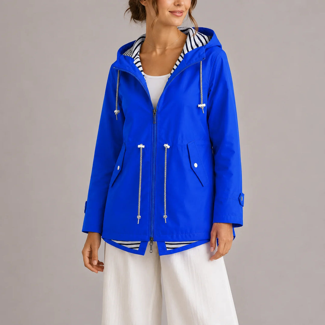 Women's hooded raincoat styled with white trousers for casual spring look