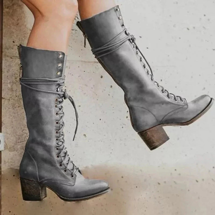 Close-up view of lace-up knee-high boots showing metal eyelets and side zip closure