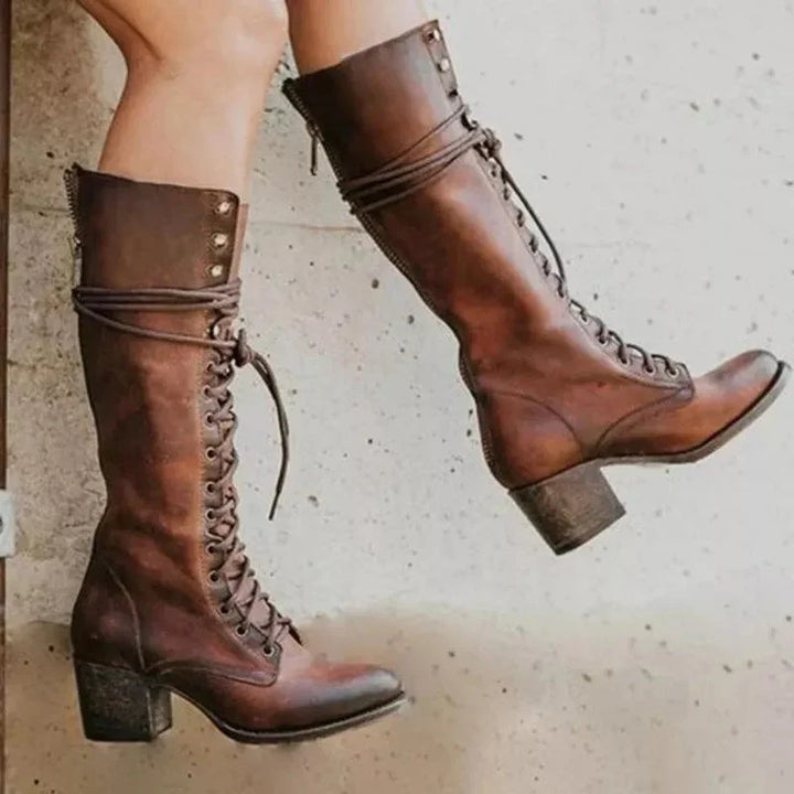 Side profile of women's knee-high boots with decorative studs and wrap-around lace detail