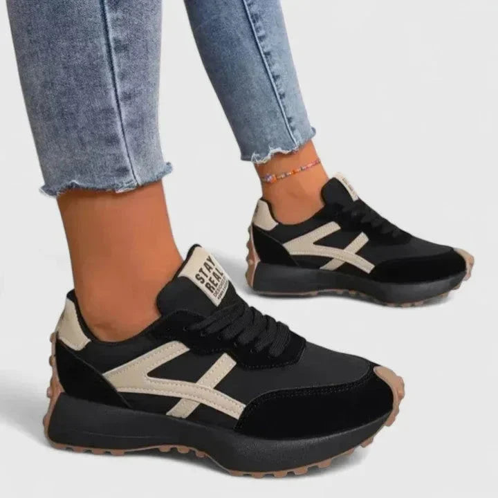 Women's retro trainers with contrast stripe detail and chunky sole worn with cropped jeans