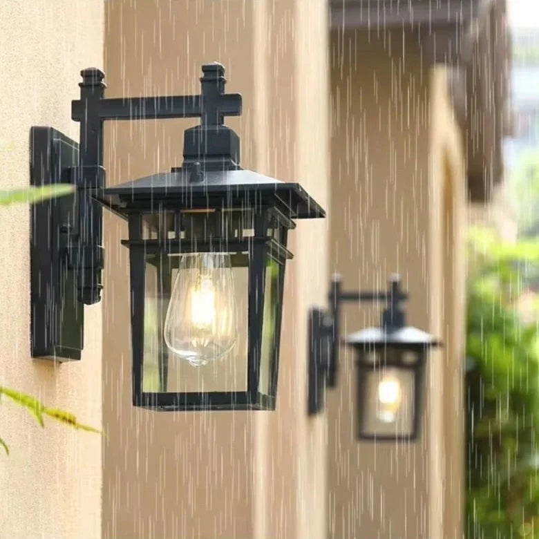 Outdoor lantern wall light illuminated at dusk showing warm light diffusion through glass