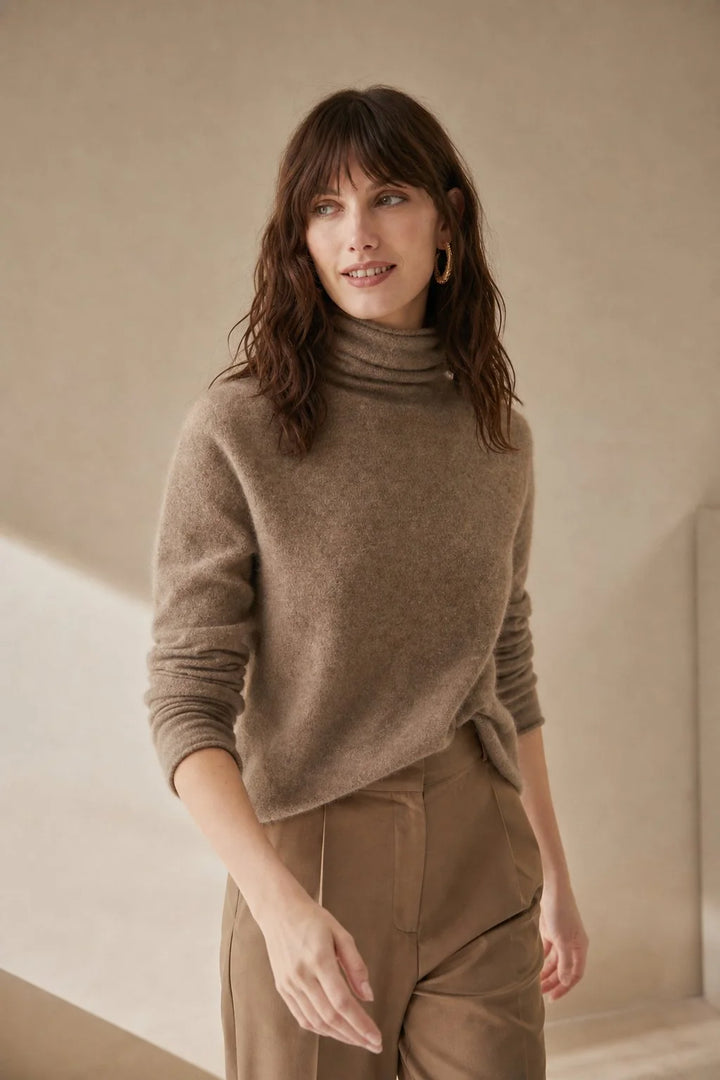 Close view of women's cashmere turtleneck showing the roll neck collar and smooth fabric finish in a warm taupe tone