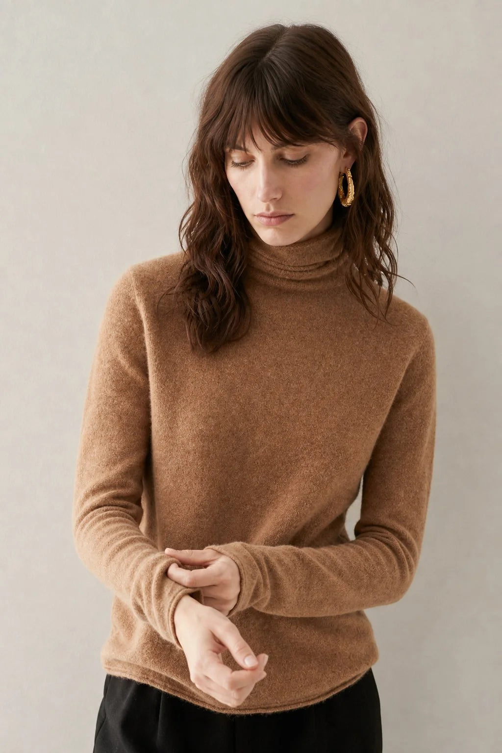 Detail of the turtleneck collar and shoulder seam on a women's cashmere jumper in a neutral beige shade