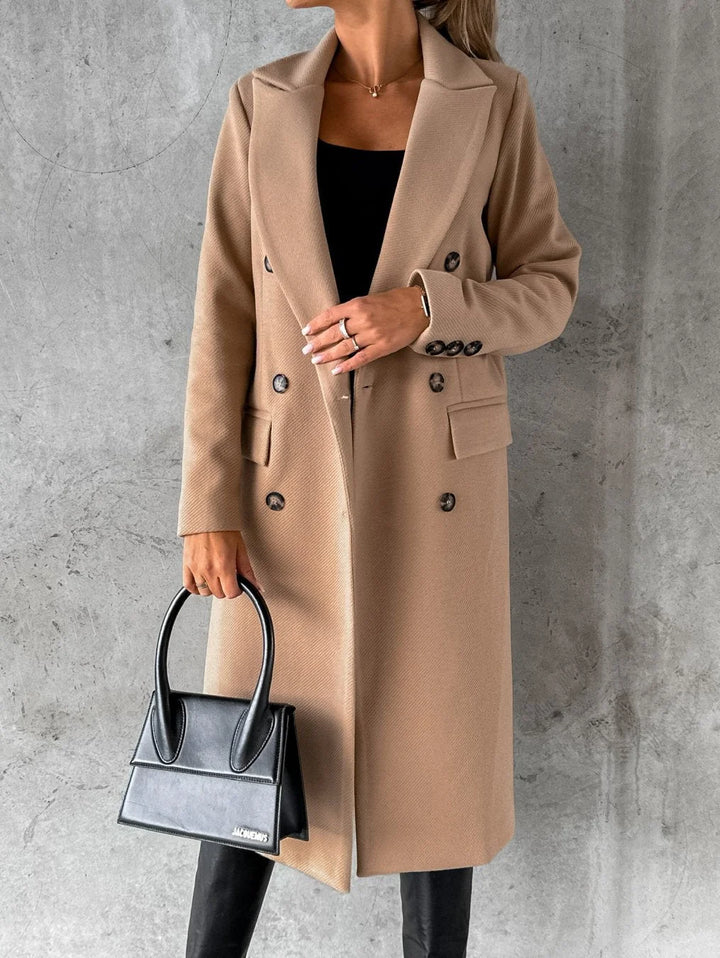 Women's tailored longline coat in neutral tone with notched lapels and button closure, styled for winter layering